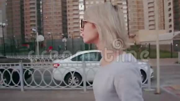 一个美丽的女人在城市里散步的侧视背景中的现代建筑近点视频的预览图