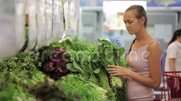 在超市挑选蔬菜的年轻女子视频的预览图