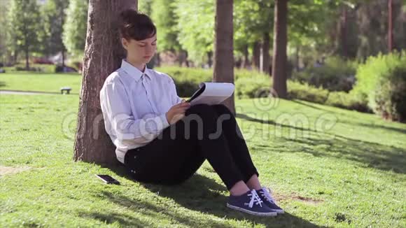 女人学生在公园里做她的任务视频的预览图