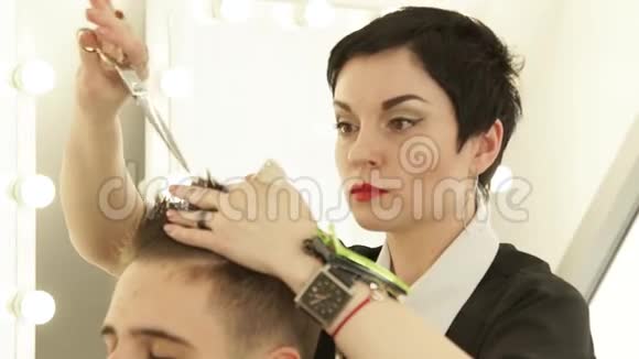 理发师用专业剪刀剪头发在美发沙龙梳头为男性剪发做特写视频的预览图
