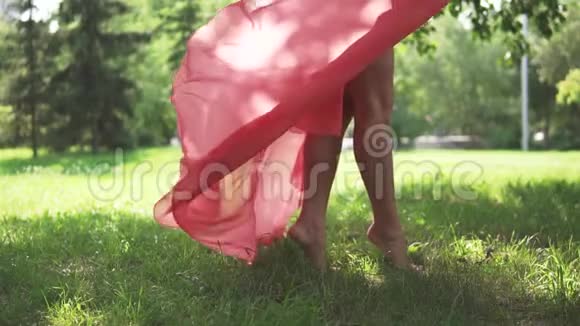 女性腿部特写穿着红色连衣裙和高跟鞋的女孩正在公园的绿色小巷里逃跑慢慢慢慢视频的预览图