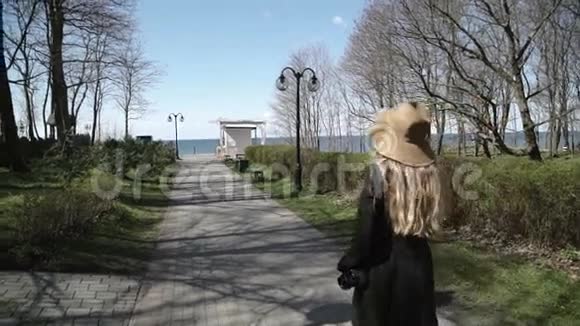 一个穿着外套和帽子的年轻女人公园去海边视频的预览图