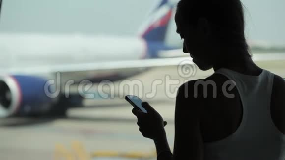 年轻女子在机场用智能手机吃零食视频的预览图