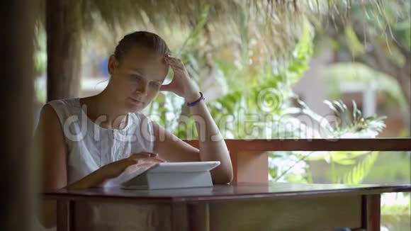 使用平板电脑的女人坐在热带户外视频的预览图
