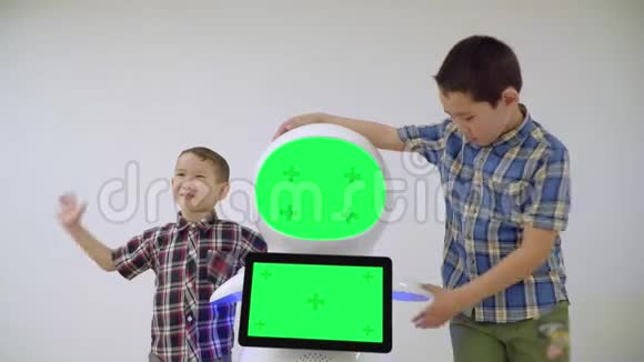 两个亚洲男孩兄弟站在一个人形机器人旁边微笑通过编程方法学习最新的机器人技术是视频的预览图