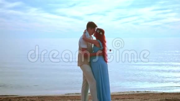 年轻人在海边接吻怀孕的情侣接吻快乐夫妻海滩视频的预览图