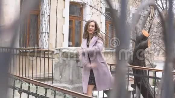 穿外套的女孩在街边的栅栏后面摆姿势视频的预览图