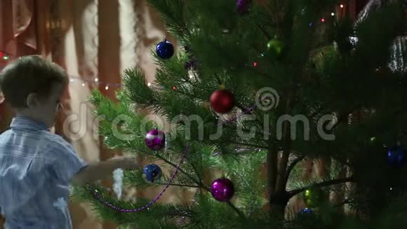 男孩把纸雪花挂在圣诞树上视频的预览图