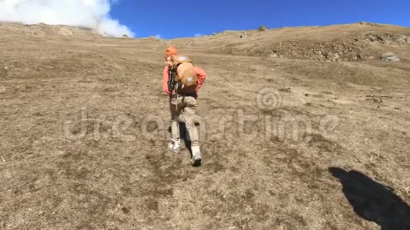 两个戴着帽子和太阳镜背包的游客摄影师带着相机在黄草上山视频的预览图