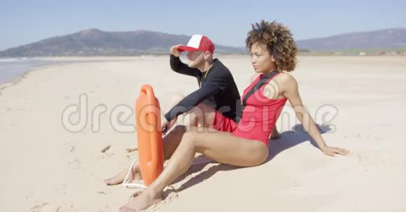 坐在沙滩上的男女救生员视频的预览图