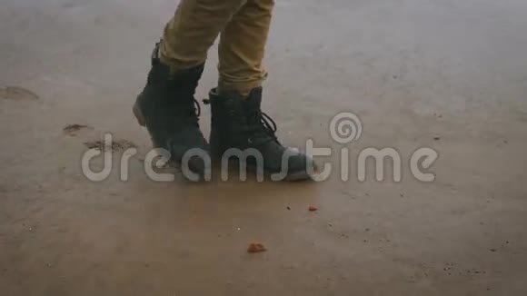 一个穿着芥末裤和黑色时髦鞋子的年轻人独自在海滩上散步散步男孩视频的预览图