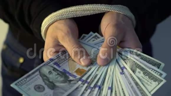 男性手握着绳子握着一堆钱美元钞票金融领域的概念视频的预览图