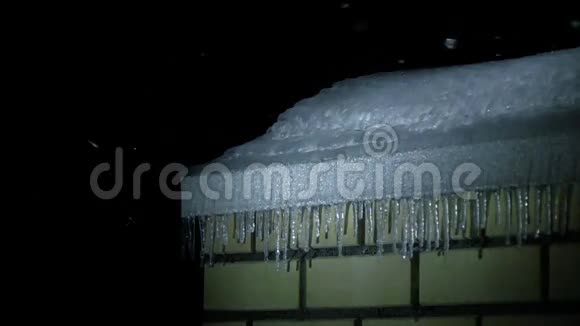 砖楼屋顶的冰柱和夜间降雪的超级慢镜头视频的预览图