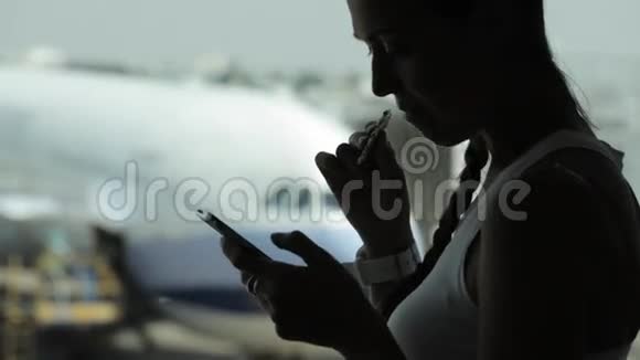 年轻女子在机场用智能手机吃零食视频的预览图