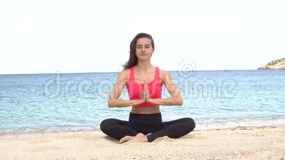 日落时分年轻女子在海滩上练习瑜伽锻炼冷静与和谐沉思于莲姿健康视频的预览图
