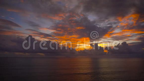 在平静的海景中明亮橙色黄色的夕阳穿过靠近水的积云视频的预览图