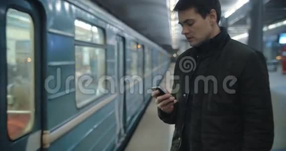 站在地铁站台上打短信的男子视频的预览图