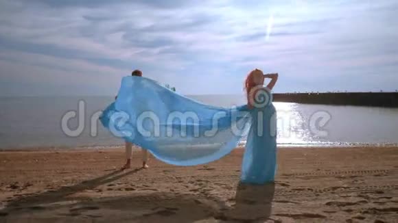 在海边怀孕的女人穿着蓝色衣服的孕妇在风中飞扬视频的预览图