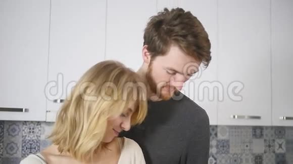 快乐的一对夫妇在厨房做饭而男人在家里吻她的女朋友视频的预览图