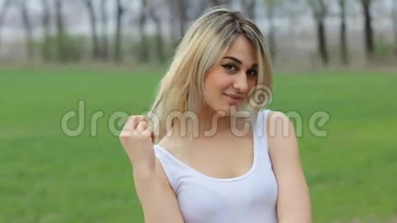 微笑迷人的女孩在花园里看着她的肩膀在镜头视频的预览图