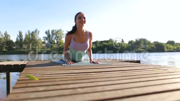 年轻女子在木桥上做瑜伽体育运动视频的预览图