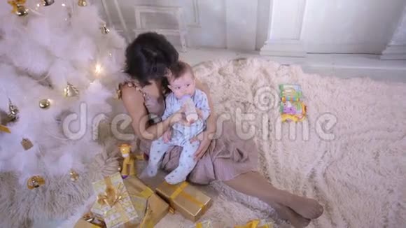 圣诞家庭概念新年庆祝时妈妈在圣诞树旁喂孩子视频的预览图