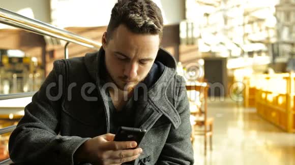 一个男人在一个大型购物中心的咖啡馆里用电话视频的预览图