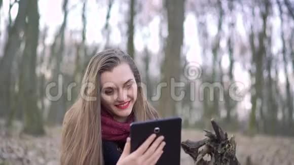 一个在森林里用平板电脑的女孩的特写脸4k视频的预览图