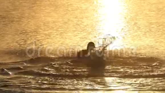 在令人惊叹的夕阳西下年轻人在湖中游蝶视频的预览图