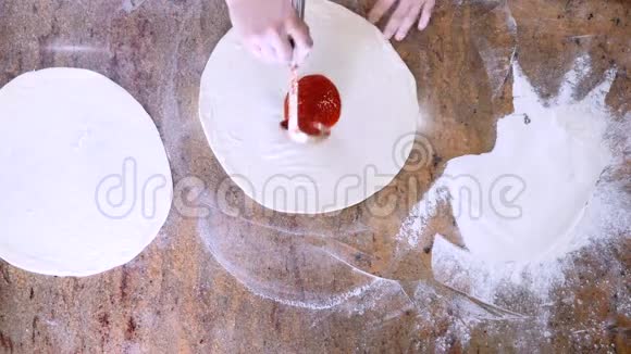 上面的番茄酱被涂抹在披萨面团上视频的预览图