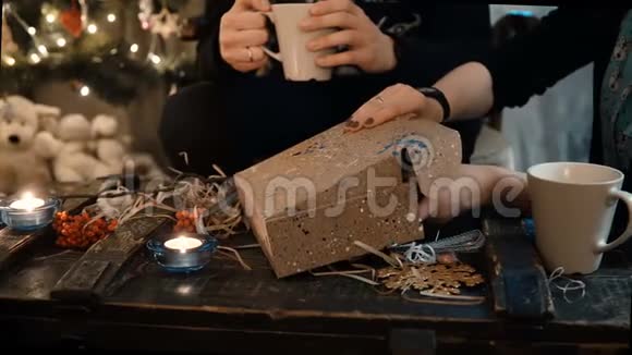 近距离观看年轻夫妇坐在桌子上打开礼物盒与礼物圣诞节的气氛视频的预览图