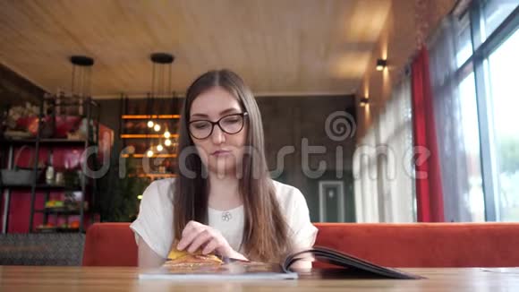 快乐女孩在咖啡馆吃饭看菜单餐厅视频的预览图