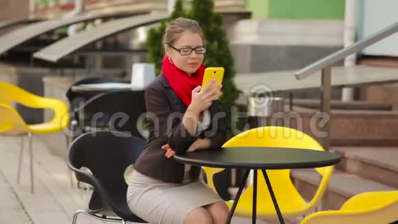 女商人在咖啡馆的餐桌上看着智能手机视频的预览图
