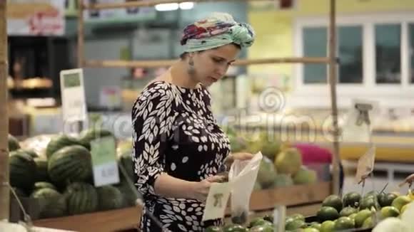 超市里年轻有魅力的女人挑选水果和蔬菜视频的预览图