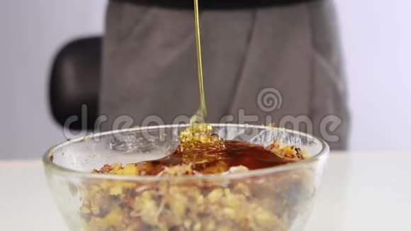 妇女在坚果黄油中加入蜂蜜并在碗中混合配料视频的预览图