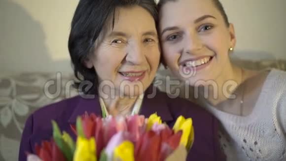 祖母带着鲜花和孙女在镜头上微笑慢慢地视频的预览图