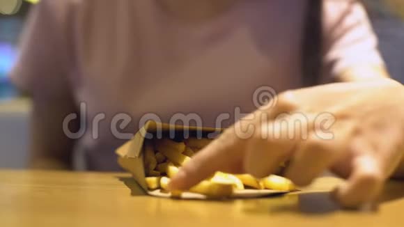 年轻女性在快餐店吃脆炸薯条吃不健康的零食视频的预览图