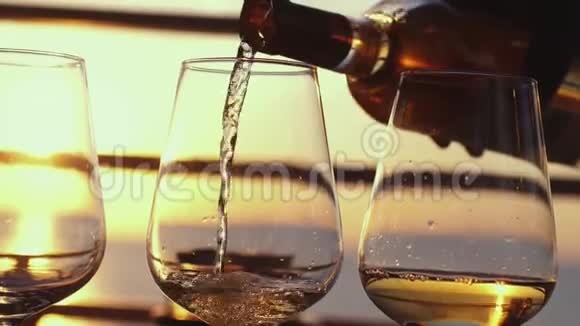 在日落时分的餐厅露台上在海边的酒杯里斟满白葡萄酒以慢动作庆祝3840x2160视频的预览图