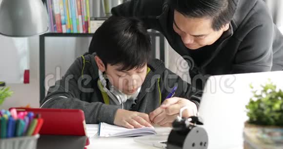 亚洲父子在客厅的桌子上做作业视频的预览图