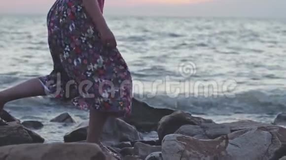 一个穿着长裙子在岩石海滩上慢动作的女人3840x2160视频的预览图