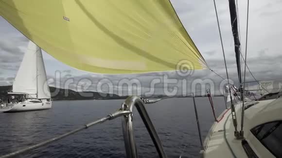 一艘白色游艇的甲板在一艘黄色的帆船下航行视频的预览图