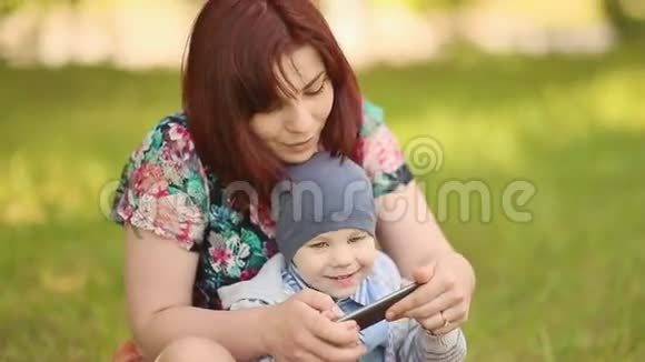 母亲和孩子在草地上玩电话游戏视频的预览图
