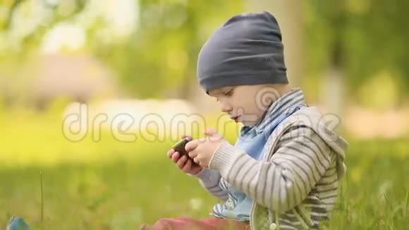 三岁的宝宝在草地上玩电话视频的预览图