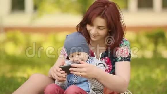 母亲和孩子在草地上玩电话游戏视频的预览图