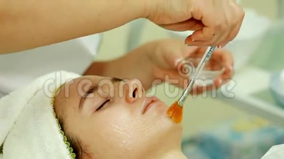 特写镜头美容师用刷子在脸上溅上特殊的药水视频的预览图