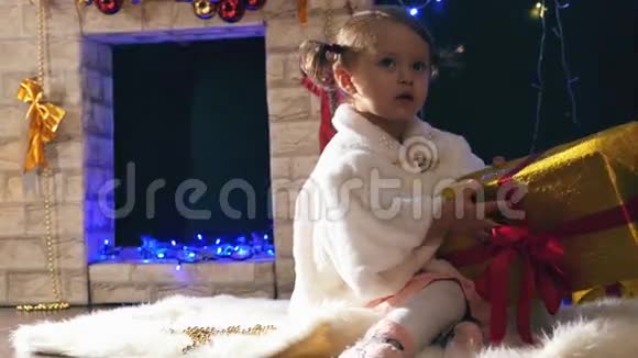 女孩在壁炉旁打开圣诞礼物盒装饰了圣诞树视频的预览图