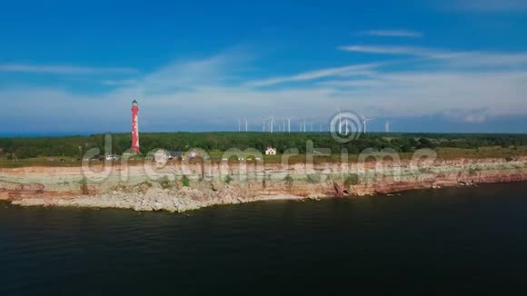 从海上和陆地上的老灯塔和风力涡轮机的力量鸟瞰海岸线视频的预览图