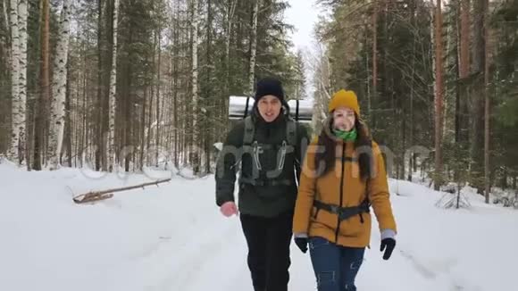 一个年轻人和一个女孩正沿着一条冬天的森林小径散步视频的预览图