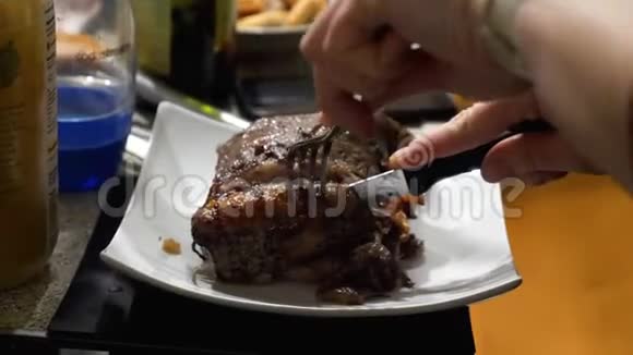 女用手在繁忙的餐桌上用叉子和刀切烤牛肉视频的预览图