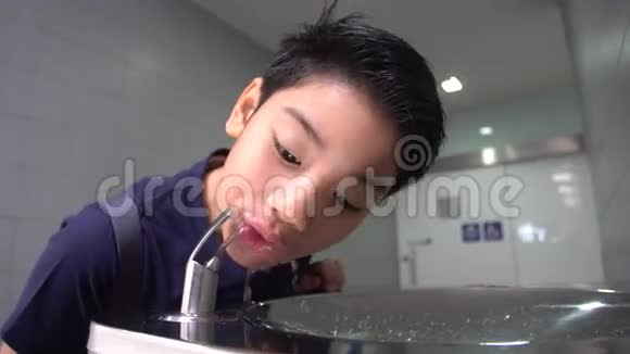 亚洲饥饿的男孩从水管里喝水视频的预览图